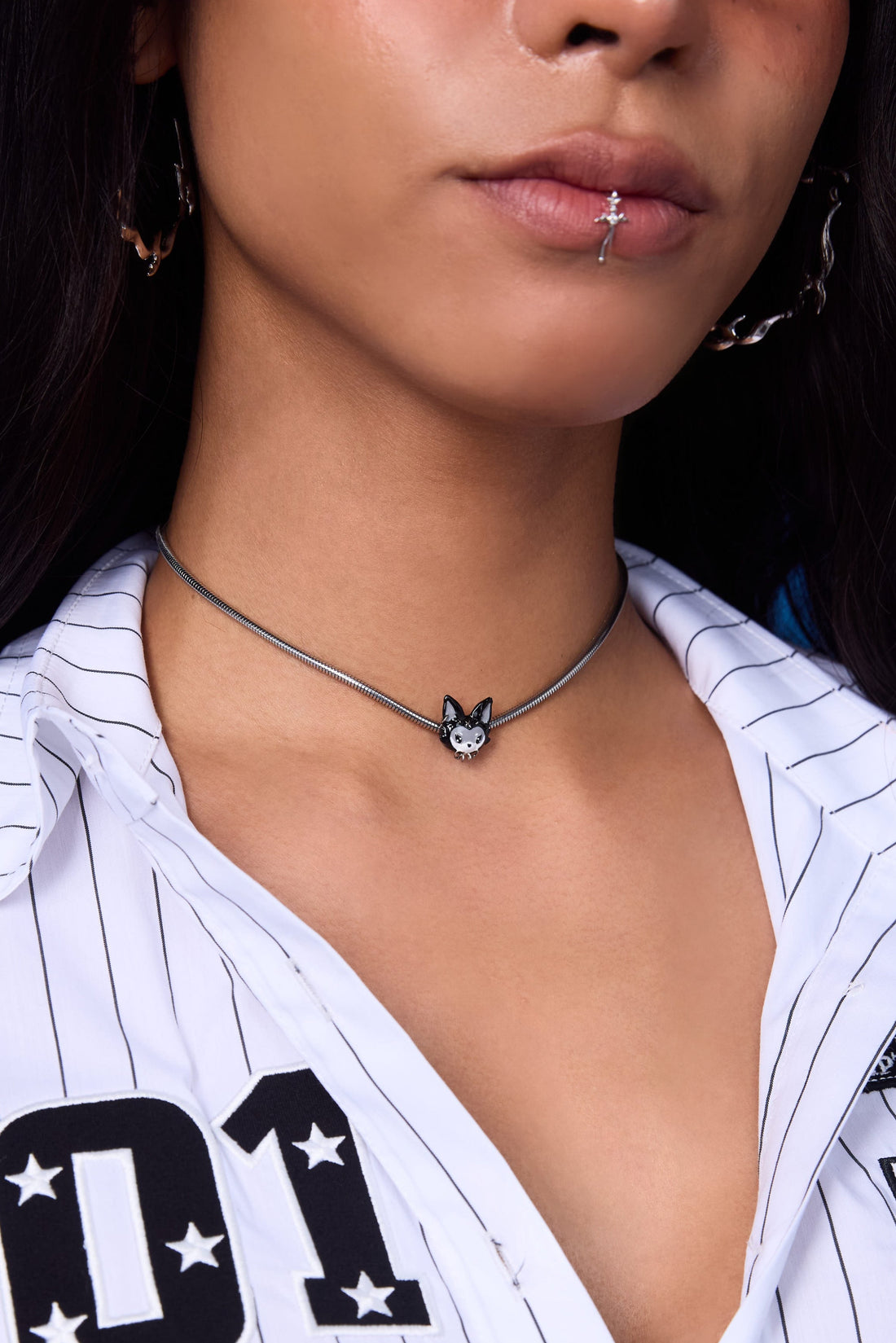 FEFE Dog Choker close-up on model — silver snake chain choker with black and white FEFE dog face charm, worn at collarbone with white pinstripe shirt and glasses